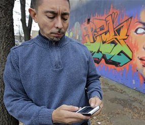 In this Dec. 6, 2013 photo, Eddie Bocanegra, co-executive director of the YMCA of Metropolitan Chicago's Youth Safety and Violence Prevention program, stands with his phone outside the organization's center in Chicago.