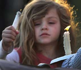 Addie Delisle lights her candle during a vigil for slain Police chief Michael Maloney, Friday, April 13, 2012 in Greenland, N.H. Maloney was trying to serve a search warrant Thursday night when a suspect opened fire, killing the 48-year-old chief, injuring four officers from other departments, and plunging the southeastern New Hampshire community of Greenland into a grief that residents say they won't soon get over.