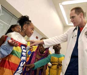 Dr. Ernest G. Bertha, right, director of Pediatric Emergency Medicine at Temple University Children's Medical Center in Philadelphia, points out a reflective safety panel on a Halloween costume worn by Nakera Blair, 8, of Philadelphia, Tuesday, Oct. 14, 2003. (AP Image)