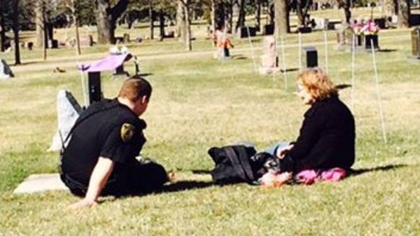 heartbreaking police photos. officer comforts woman at son's gravestone