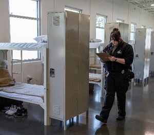 Corrections Officer Tracy Donovan writes in a clip board as she walks past rows of beds at a new facility at the Community Corrections Center in Lincoln, Neb., Thursday, Sept. 28, 2017.