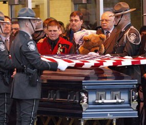 A Pennsylvania State Police honor guard folds the flag over the casket containing the remains of Pennsylvania State Trooper Paul G. Richey during a memorial service. Richey, a 16-year veteran, was killed by a gunman lying in wait while answering a domestic call.