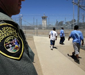 In this photo taken June 20, 2018, inmates pass a Correctional Officer as they leave an exercise yard at the California Medical Facility in Vacaville, Calif.