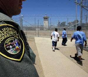 In this photo taken June 20, 2018, inmates pass a Correctional Officer as they leave an exercise yard at the California Medical Facility in Vacaville, Calif.
