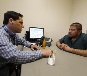 In this Tuesday, March 1, 2016, photograph, Dr. Josh Blum, left, confers with inmate Lee Gonzales at the Denver County Jail in downtown Denver.
