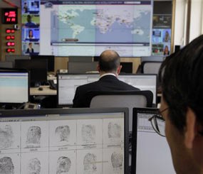 An Interpol employee looks at finger prints in the control room of the Interpol headquarters in Lyon, central France, Friday, June 22, 2012. International police agency Interpol is involved in the security of the London 2012 Olympic Games. Fighter jets thunder above the English countryside. Missiles stand ready. And Big Brother is watching like never before.
