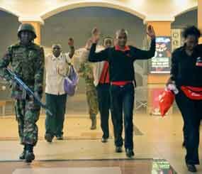 Civilians who had been hiding during gunbattles hold their hands in the air as a precautionary measure before being searched by armed police leading them to safety, inside the Westgate Mall in Nairobi, Kenya on Sept. 21. (AP Image)