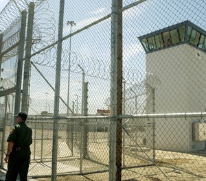 A correctional officer walks near a gate, which is one of two entrances into Kern Valley State Prison Tuesday, June 14, 2005, in Delano, Calif. (AP Photo/Ric Francis)