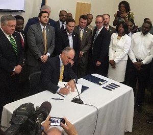 In this June 15, 2017 photo, a bipartisan group of lawmakers surround Louisiana Gov. John Bel Edwards as he signs 10 criminal justice bills into law during a ceremony in Baton Rouge, La.