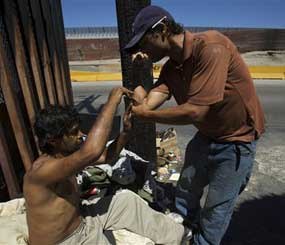 Drug addicts help each other get high at a street corner near the international border in Tijuana, Mexico Tuesday, Aug. 25, 2009. Mexico now has some of the most liberal laws in the world for drug users after eliminating jail time for tiny amounts of marijuana, cocaine and even heroin, LSD and methamphetamine. (AP Photo/Guillermo Arias)