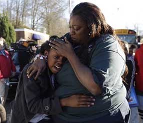 A woman comforts a child after after a shooting at an Price Middle school in Atlanta on Thursday, Jan. 31, 2013. A 14-year-old boy was wounded outside the school Thursday afternoon and a fellow student was in custody as a suspect, authorities said. No other students were hurt.