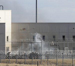 Prisoners burn objects as they mill in a courtyard behind razor wire at the Tecumseh State Correctional Institution in Tecumseh, Neb., Thursday, March 2, 2017.