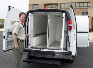 Capt. Steve Snow, director of security at the Frederick County Adult Detention Center, on Monday stands beside the 2013 Chevy van used to transport prisoners. The van has two compartments in the back that can hold six and four people and one compartment that can hold two people. (Photo Sam Yu/Frederick News-Post)