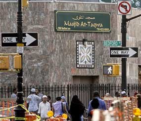 People pass below a New York Police Department security camera above a mosque in the Brooklyn. Working with the CIA, the NYPD maintained a list of “ancestries of interest” and dispatched undercover officers to monitor Muslim businesses and social groups