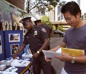 Mark Jheng, 24, right, takes an application for the New York Police Department on a street outside police headquarters.