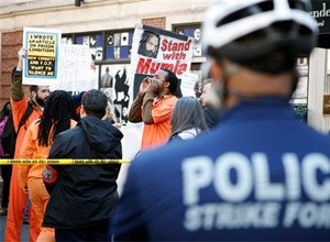 Several dozen supporters of Mumia Abu-Jamal, some dressed in orange, prison-like jumpsuits, protest near the Re-victimization Relief Act bill signing Tuesday Oct. 21, 2014, in Philadelphia. (AP Photo/Michael Sisak)