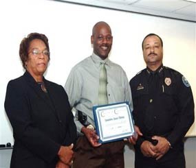 In this 2008 image provided by the Jackson, Miss. Police, Detective Eric Smith, center, flanked by Chief Rebecca Coleman, left, and Assistant Chief Lee Vance accepts the Certificate of Commendation.