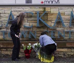 Leslie King, right and Tenille Beseda place flowers Wednesday Dec. 12, 2012, at the entrance to the scene of a multiple shooting yesterday at Clackamas Town Center Mall in Portland, Ore. A gunman who opened fire on shoppers at the mall had no connection to the two people he fatally shot and wanted to kill as many people as possible, police said Wednesday.