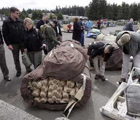 In this May 2, 2012 photo, law enforcement and other officials examine surplus gear at Joint Base Lewis McChord in Washington state as they attend an information session for a program that distributes surplus military equipment to state law-enforcement agencies.