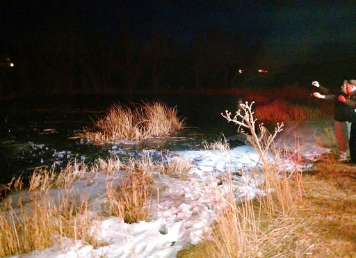 A search and rescue team work on the edge of a frozen pond.