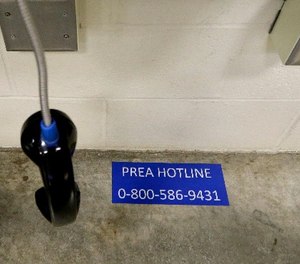 In this photo taken Oct. 17, 2014, the PREA hotline number for offenders to call is pasted on the floor under a bank of phones at the Washington Corrections Center For Women in Gig Harbor, Wash.