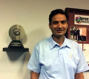 Gautam Malik, chief operating officer, stands next to the 2015 Governor's Export Achievement Award.