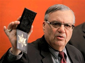 In this Dec. 21, 2011 file photo, Maricopa County Sheriff Joe Arpaio shows his badge as he holds a ceremony where 92 of his immigration jail officers, who lost their federal power to check whether inmates are in the county illegally, turn in their credentials after federal officials pulled the Sheriff's office immigration enforcement powers in Phoenix. (AP Photo/Ross D. Franklin, File)

