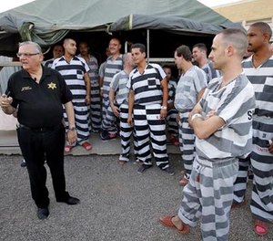 In this , June 23, 2012, file photo, inmates gather next to Maricopa County Sheriff Joe Arpaio as he walks through a Maricopa County Sheriff's Office jail called