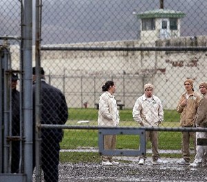 In this file photo taken Jan. 28, 2016, inmates mingle in a recreation yard in view of COs, left, at the Monroe Correctional Complex in Monroe, Wash.
