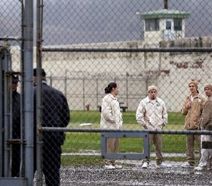 In this file photo taken Jan. 28, 2016, inmates mingle in a recreation yard in view of COs, left, at the Monroe Correctional Complex in Monroe, Wash.