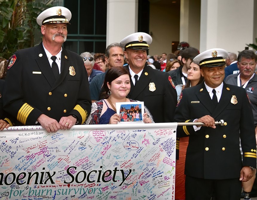 Anaheim Fire & Rescue Chief Pat Russell (left) joins others in a Walk of Remembrance on Wednesday, Oct. 2, at the Phoenix World Burn Congress outside the Anaheim Convention Center. Also pictured is burn victim Hope Henkel, holding a picture of her deceased family. (Photos/Steven Georges/Behind the Badge)