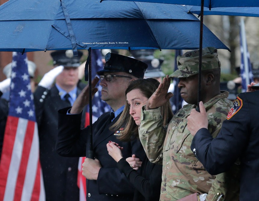 Shannon Slutman, wife of Staff Sgt. Christopher Slutman, watches as a casket containing her husband's body is moved into a funeral home in the Bronx borough of New York, Monday, April 22, 2019. Firefighters in three states are honoring the U.S. Marine and New York City firefighter who was killed by a roadside bomb in Afghanistan. (AP Photo/Seth Wenig)
