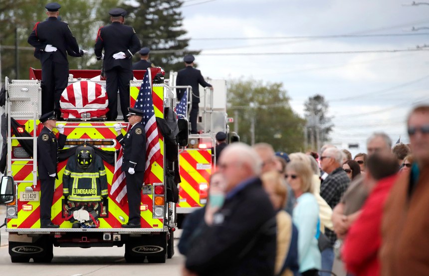 Members of the community gather along West Wisconsin Avenue during the funeral procession for Appleton firefighter Mitchell F. Lundgaard, as it makes its way toward the Appleton Alliance Church on Monday, May 20, 2019, in Appleton, Wis. The 14-year veteran of the Appleton Fire Department was fatally shot while responding to a medical emergency at the downtown Valley Transit Center on Wednesday, May 15, 2019 in Appleton, Wis. (Danny Damiani/The Post-Crescent via AP)
