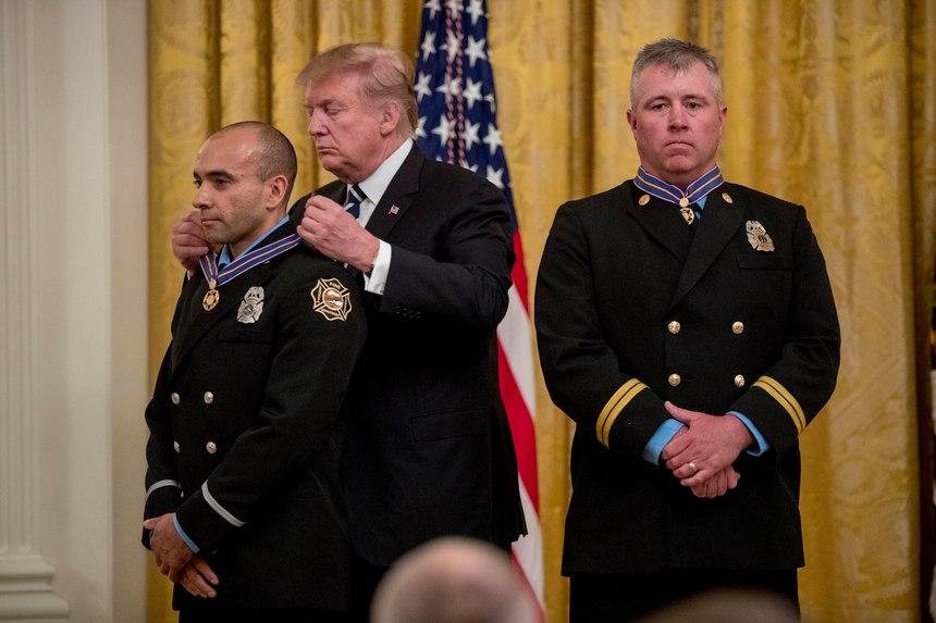 President Donald Trump awards Fire Captain Dustin Moore, right, and Firefighter Paramedic Andrew Freisner, left, of the Lenexa Fire Department, Kansas, the Public Safety Officer Medal of Valor at a ceremony in the East Room of the White House in Washington, Wednesday, May 22, 2019.