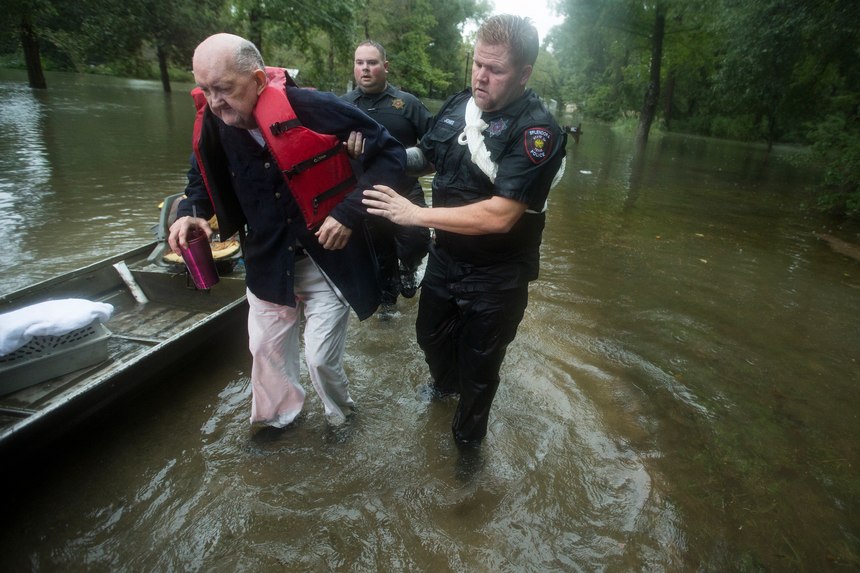 Fred Stewart, left, is helped to high ground by Splendora Police officer Mike Jones after he was rescued from his flooded neighborhood as rains from Tropical Depression Imelda inundated the area, Thursday, Sept. 19, 2019, in Splendora, Texas.