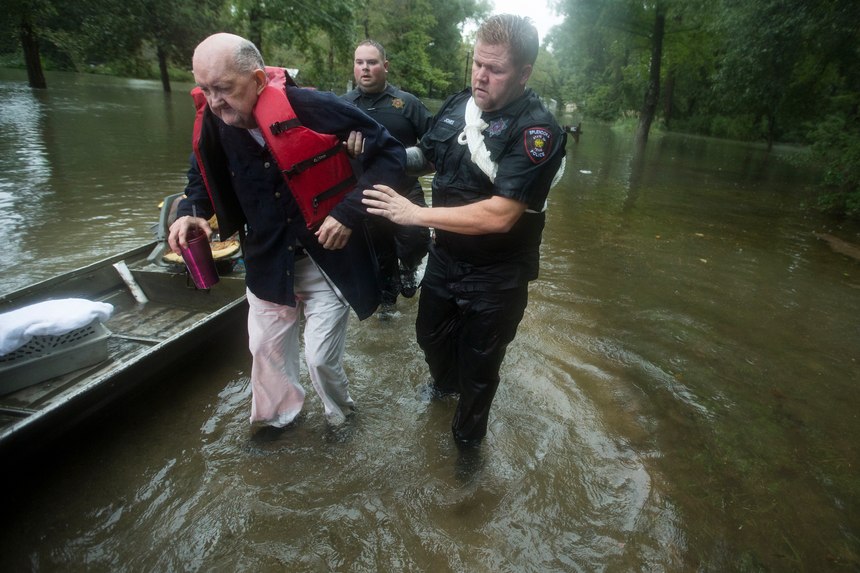 Fred Stewart, left, is helped to high ground by Splendora Police officer Mike Jones after he was rescued from his flooded neighborhood as rains from Tropical Depression Imelda inundated the area, Thursday, Sept. 19, 2019, in Splendora, Texas.