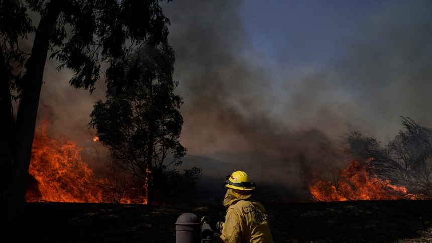 A firefighter watches flames from the Silverado Fire, Monday, Oct. 26, 2020, in Irvine, Calif. A fast-moving wildfire forced evacuation orders for 60,000 people in Southern California on Monday as powerful winds across the state prompted power to be cut to hundreds of thousands to prevent utility equipment from sparking new blazes.