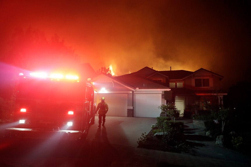 A firefighter walks next to an engine as crews make a stand in front of an advancing wildfire in a residential neighborhood Friday, Nov. 9, 2018, in West Hills, Calif.
