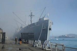 Fire officials stand in front of the SS Jeremiah O'Brien ship after a fire broke out before dawn at Fisherman's Wharf in San Francisco. (AP Photo/Jeff Chiu)