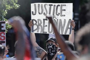 A protester holds a sign during a protest over the deaths of George Floyd and Breonna Taylor, Monday, June 1, 2020, in Louisville, Ky.