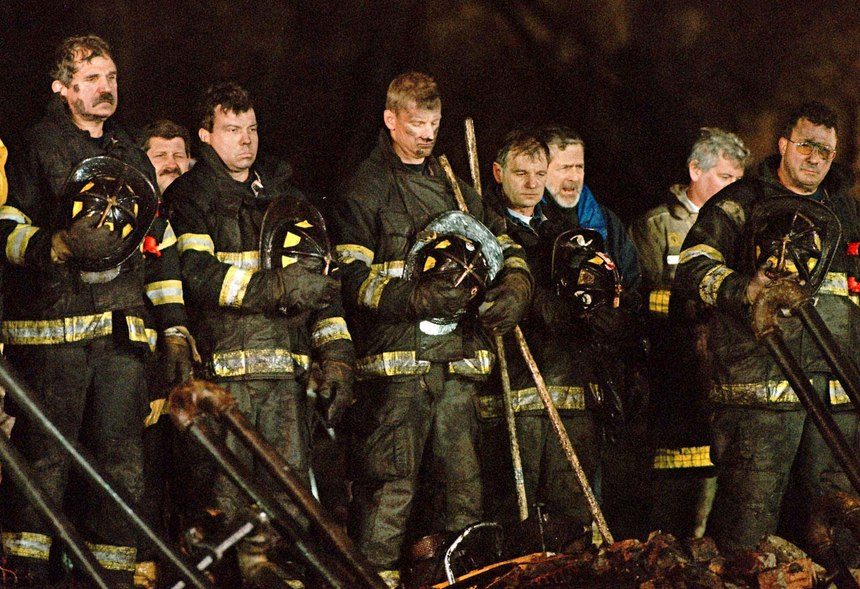 Firefighters stand for a moment of silence on Dec. 10, 1999, at 6:13 p.m. exactly one week after the first alarm sounded for the Worcester Cold Storage and Warehouse Co. building fire, which killed six firefighters in Worcester Mass.