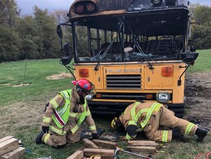 Two Lee's Summit firefighters examine a burned school bus.