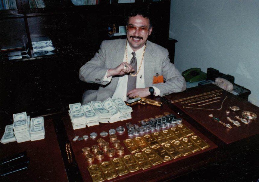 Javier poses with gold and stacks of cash seized from an Escobar safe house in Medellin during the Escobar manhunt.