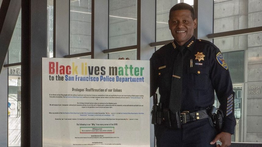 San Francisco Chief of Police Bill Scott stands with a 'Black lives matter' poster.