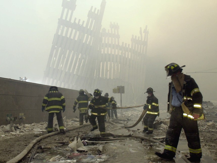 With the skeleton of the World Trade Center twin towers in the background, FDNY firefighters work amid debris on Cortlandt St. after the terrorist attacks of Tuesday, Sept. 11, 2001.