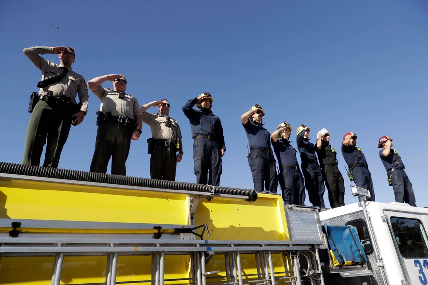 Law enforcement and fire personnel salute from an overpass as a motorcade with the body of Sgt. Ron Helus passes by Thursday, Nov. 8, 2018, in Newbury Park, Calif. Helus was fatally shot while responding to a mass shooting at a country music bar in Southern California.