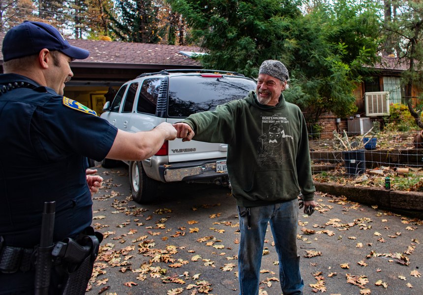 Paradise Police Officer Perry Walters checks on the welfare of resident Brad Weldon, who refused to leave his property during the fire, on Nov. 26, 2018 in Paradise, Calif. Weldon is grateful that the police bring him and his 90-year-old mother supplies, but he questions why he isn't allowed to leave to get supplies himself and return. Once he leaves, he won't be allowed back. Most of the homes around Weldon's burned to the ground, though Weldon's was unscathed.