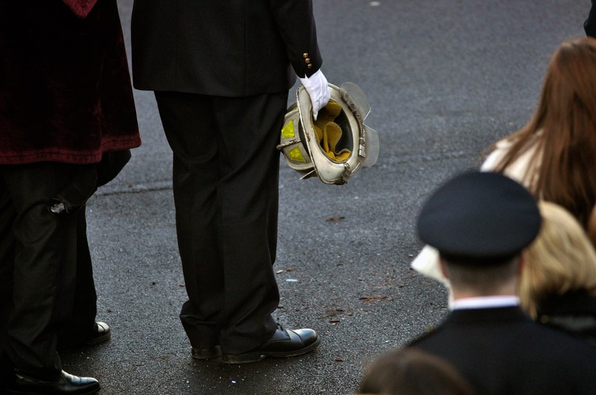 Nicholas Chiapperini holds the helmet of his father, Lt. Mike Chiapperini, during a funeral service in Webster, N.Y. Lt. Mike Chiapperini and fellow firefighter Tomasz Kaczowka were slain by a gunman in a fiery Christmas Eve ambush.