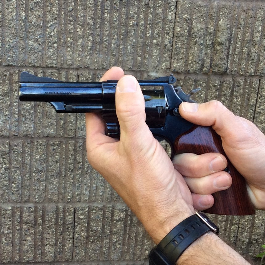 The latch on this Smith & Wesson needs to be pushed forward with your thumb to unlock the cylinder. Other guns may require you to pull the latch to the rear, or push it in towards the frame to unlock the cylinder.