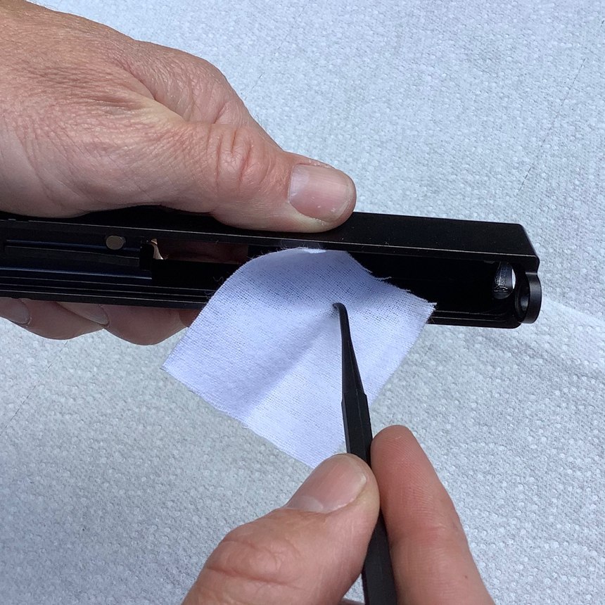 It’s hard to get the slide rails clean with just your finger and a rag. Use a tool to push a patch into the groove, and drag it along the length of the rail to get the crud out.